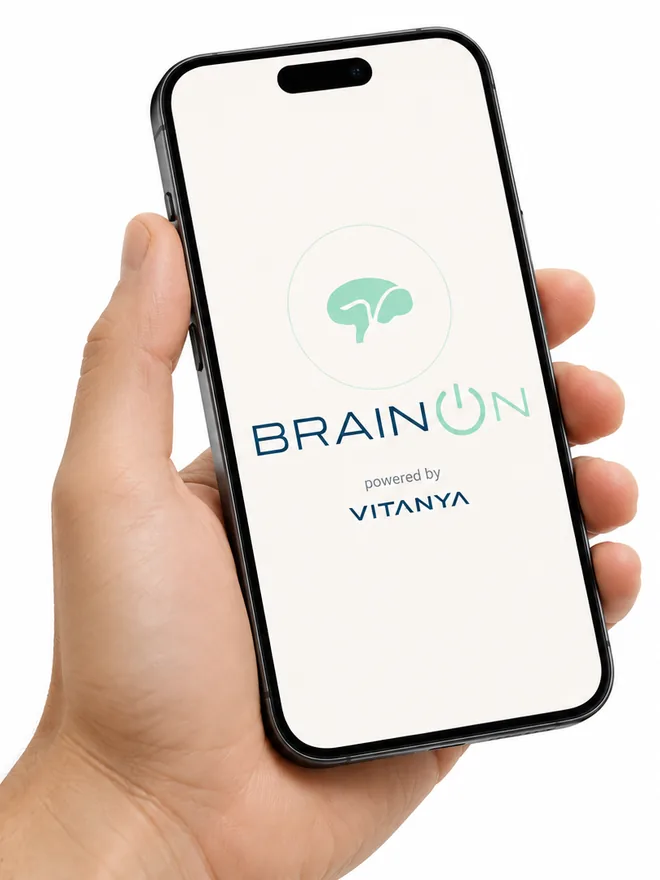 A hand holding a phone showing the BrainOn app, powered by Vitanya