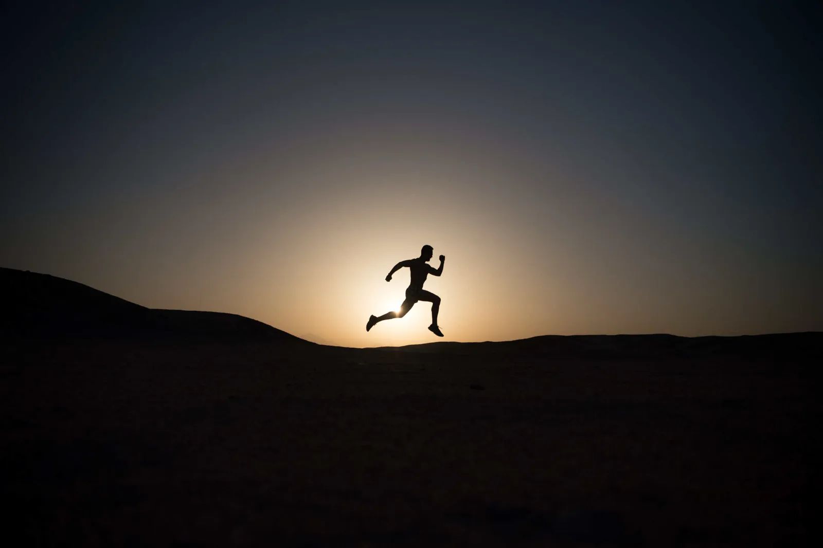 Runner silhouetted against the sunrise in open desert