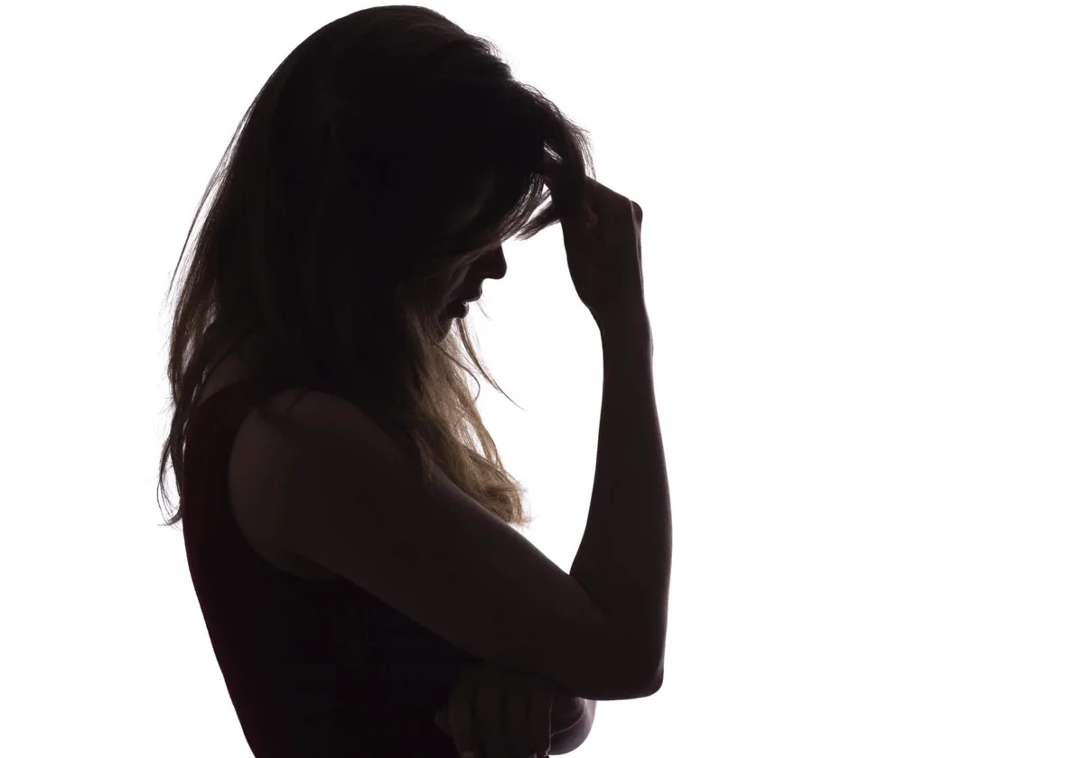 Silhouette of a woman resting her hand against her forehead